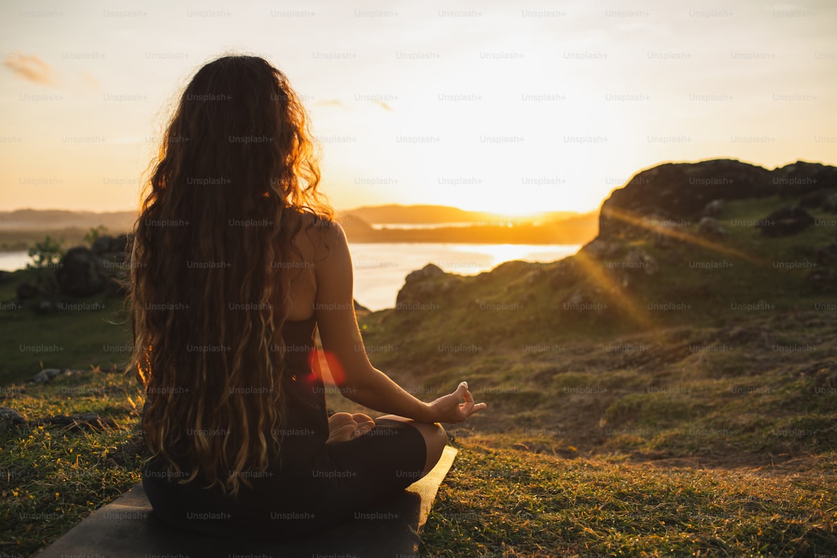 Woman meditating at sunrise overlooking mountains