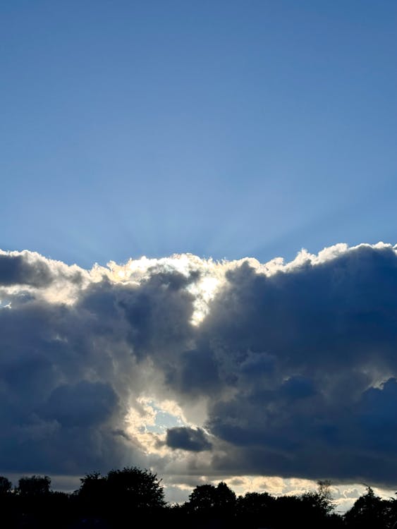 Sunlight breaking through dramatic clouds representing clarity and readiness before psilocybin