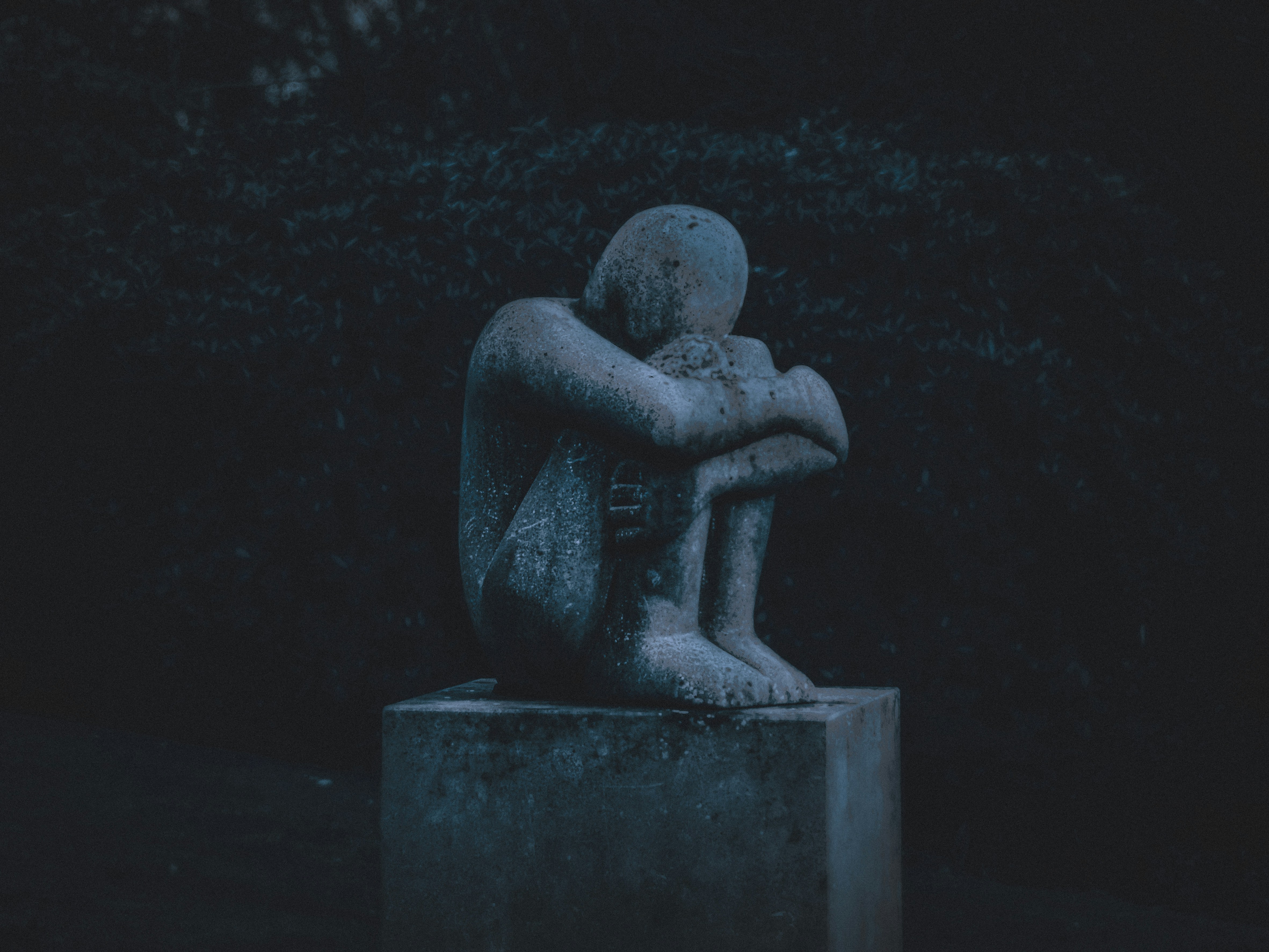 Stone sculpture of a figure curled in contemplation