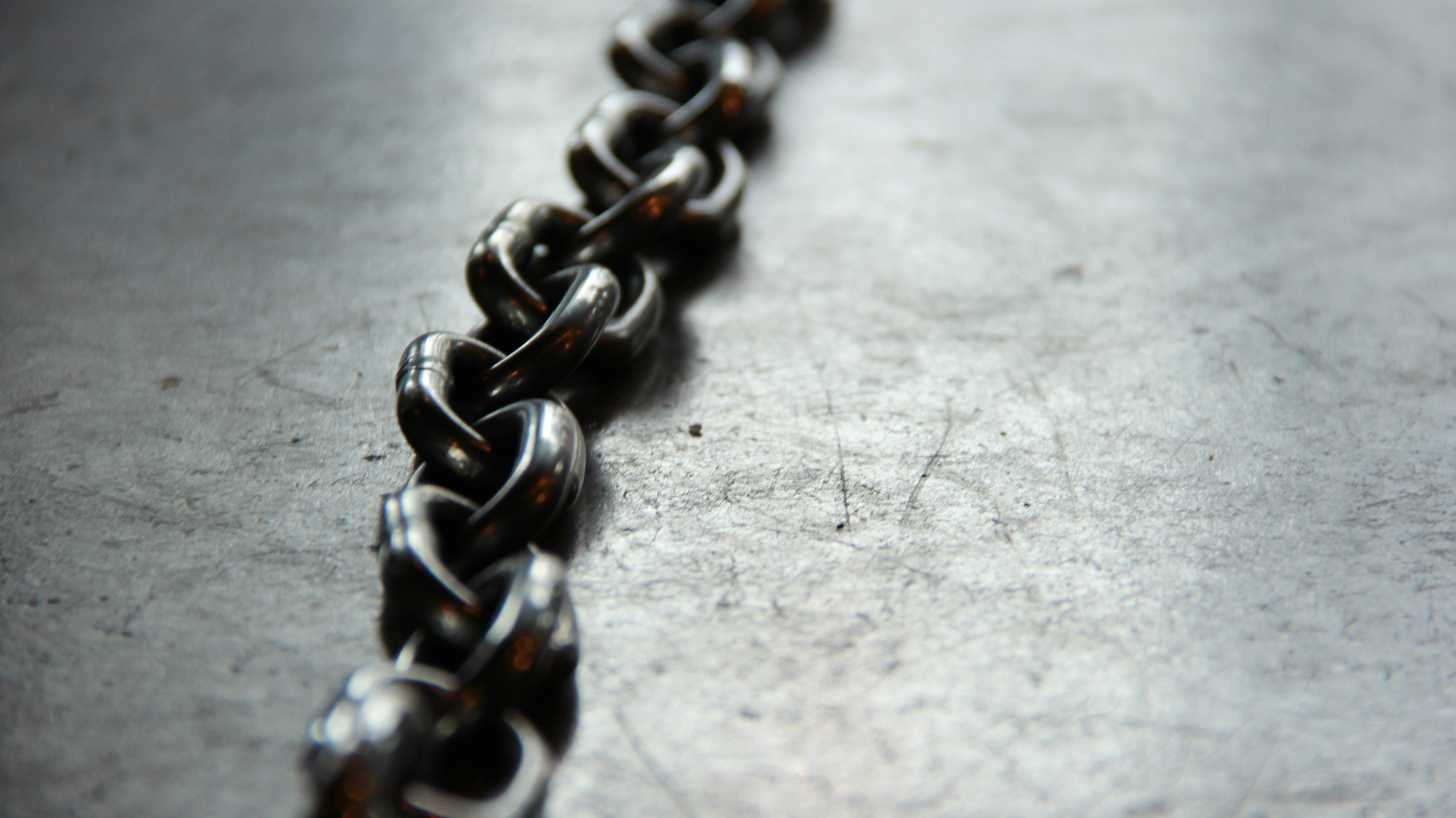 Heavy metal chain on a scratched surface symbolizing dependency